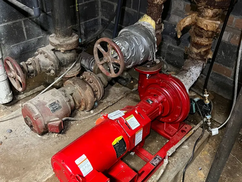 Red commercial boiler-room equipment and circulation pumps with connected piping.