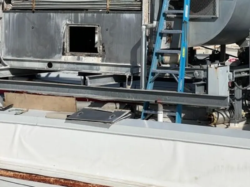 A large commercial rooftop HVAC unit accessed by a ladder for service.