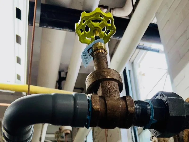 Heating-system pipework, a gas line, and a gate valve in a mechanical room.