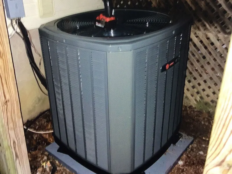 An outdoor HVAC unit installed on a pad beside a brick building.