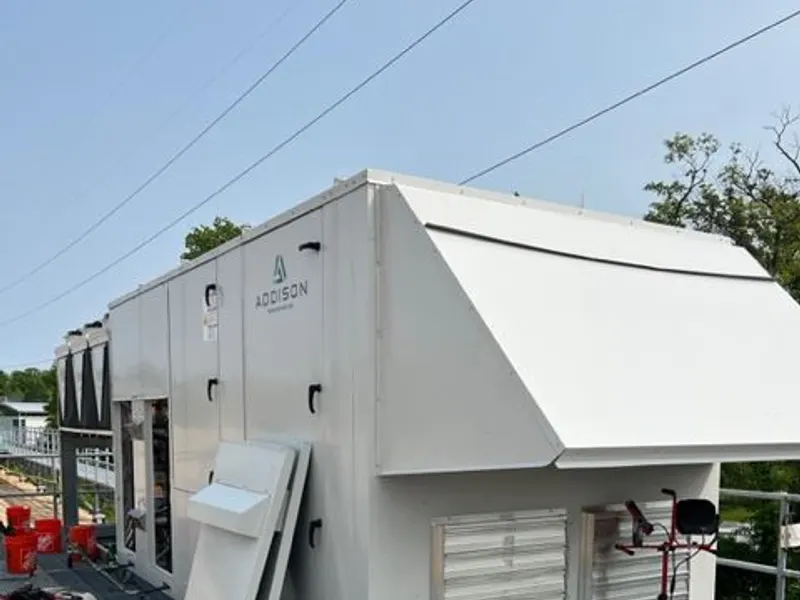 A louvered packaged HVAC unit installed on an exterior platform.