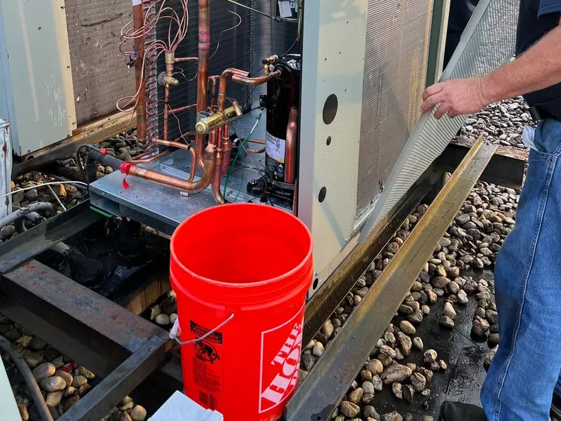 A Logan Mechanical technician servicing an outdoor HVAC unit on a job site.