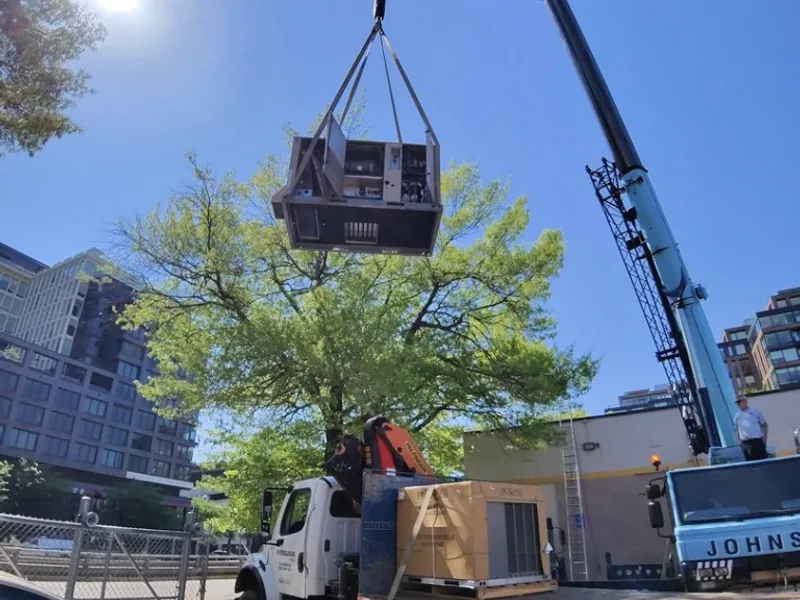 Crane setting a commercial rooftop HVAC unit on a Logan Mechanical job