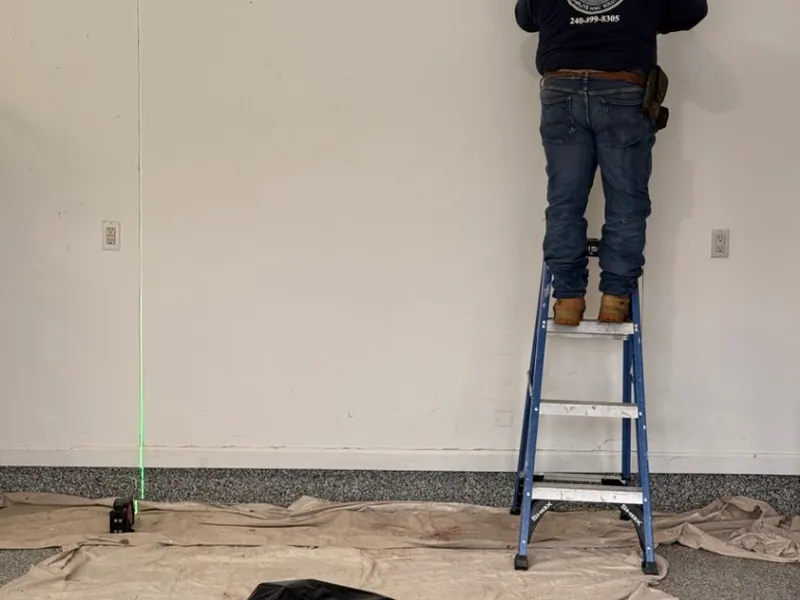 Logan Mechanical technician laying out an HVAC install with a laser level